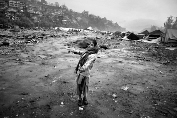 A boy playing in the rain with his balloon at the edge of spontanious camp 'Bela Noorshah' by the Neelum river in Muzzafarabad : Short Stories : Charlotte Oestervang Photography